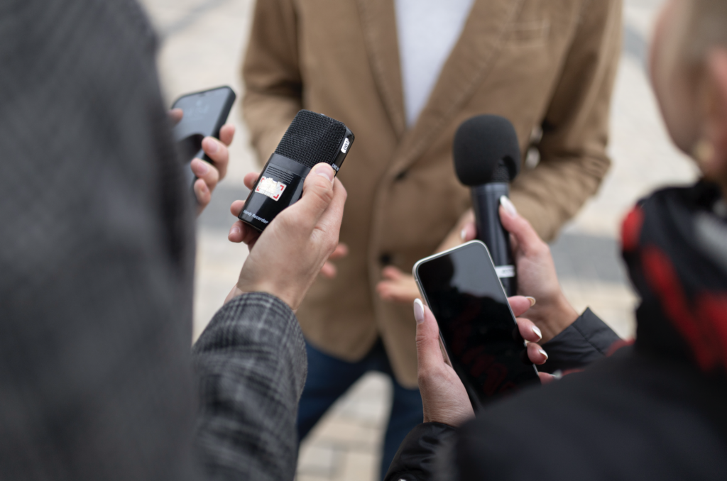 medios con microfonos en mano entrevistando a una persona.